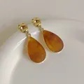 Detail of amber water-drop resin pendant with golden hammered metal texture earrings - Amber