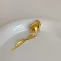 Elegant gold tulip brooch with polished metallic finish on a white ceramic plate - Gold