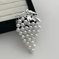 Broche de uvas vintage con hojas plateadas y perlas blancas sobre fondo blanco texturizado - Plateado