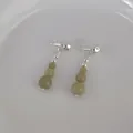 Macro detail of avocado green stone beaded tassel earrings on a ceramic dish - Natural Stone Beaded Earrings