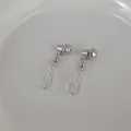 Close-up of silver beaded drop earrings with transparent beads on white ceramic tray - Glass Beaded Earrings