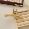 Detail of a gold alloy hair claw clip with elegant translucent beige beads on a tray - White
