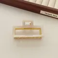 Detail van de vierkante haarclip van acryl met gouden metalen frame en marmertextuur - Feeënwit
