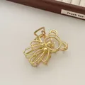 Detail view of golden metal bear hair claw with pearl accents and hollowed out design - Gold (R12)