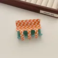 Detail of orange checkered hair claw clip with sparkly green translucent resin grip - Orange Checkerboard
