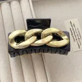 Elegant black hair claw clip with golden chain link accent on a beige jewelry tray - Black & Gold
