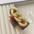 Amber resin hair claw clip with golden chain link detail on a velvet jewelry box - Amber Gold