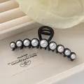 Detail of a large black claw clip featuring elegant inlaid white pearls and metal spring - Black