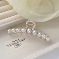 Close-up of elegant silver hair claw clip with large gradient pearls on a display box - Gold