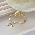 Detalle de una pinza de pelo dorada ondulada irregular con diseño de metal hueco - Dorado