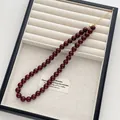Detail einer tiefroten Perlenkette mit goldenem Karabinerverschluss und Verlängerungskette - Extra Großer Durchmesser Stil