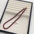 Nahaufnahme der dunkelroten Perlenkette mit goldenem Karabinerverschluss auf Leinentablett - Mittlerer Durchmesser Stil