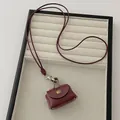 Detail view of mini burgundy leather coin purse necklace with bronze snap button - Dark Red