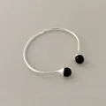 Detail of silver open bangle featuring dual black spherical beads on a textured background - Black Agate Bracelet
