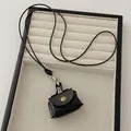 Close-up of mini black leather coin purse necklace with metal snap button and strap - Black