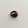Close-up of a polished wine red resin bubble ring on a minimalist textured background - Ancorra Red
