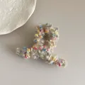 Primer plano de pinza de pelo beige de felpa con puntos de colores e hilos dorados - Beige Mixto Cruzado