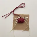 Donkerrode stoffen beer hanger met lintje op een rustieke achtergrond van jute - Rood