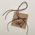 Macro-opname van een handgemaakte stoffen berenhanger met linnen textuur en strikje - Khaki