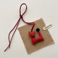 Detailed view of handmade cat charm with red polka dot fabric and plush pom-pom tail - Orange Red Bell Cat