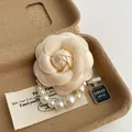 Elegante broche de camelia en tela con perlas, circonitas y colgante Good Luck - Blanco Roto