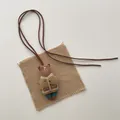 Detailed view of handmade brown bear pendant with embroidery and brown leather cord - Khaki Coat Bear