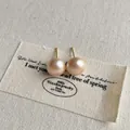 Nahaufnahme von Champagner-Perlenohrsteckern mit Goldauflage auf beigem Stoff - 10mm Stecker (A-145) / Champagner