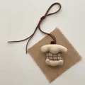 Macro detail of plush duck charm with brown checkered fabric and leather strap - Beige Plaid Fabric House (T43)