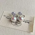 Detailansicht der weißen Perlen-Clip-Ohrringe mit vergoldeten U-Clips und weichen Pads - 10mm Clip / Irisierendes Weiß
