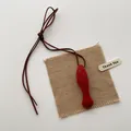 Detail shot of a red fish-shaped fabric pendant with premium suede strap and gift tag - Orange Red Fish