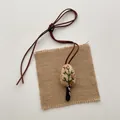 Close-up of handmade fabric necklace featuring delicate tree embroidery on canvas - Floral Little Tree