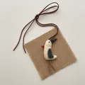 Macro view of a handmade fabric bird charm with rustic stitching and long leather cord - Long Legged Chicken with Gray Hat (T02)