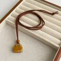 Detail of tiger eye pendant with gold metal link and brown wood bead on long rope chain - Yellow Jade Style
