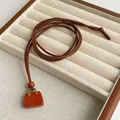 Tiger eye stone handbag pendant necklace with brown suede cord on jewelry display - Red Jasper Style