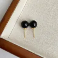 Detailansicht eleganter schwarzer Achat-Ohrstecker auf einem strukturierten Stoffdisplay - Schwarz (10mm)