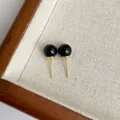Nahaufnahme minimalistischer schwarzer Achat-Ohrstecker mit Goldnadeln auf einem Tablett - Schwarz (8mm)