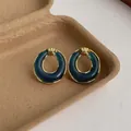 Dettaglio orecchini ovali vintage in acrilico con bordo dorato e inserti in resina blu - Blu