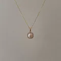 Macro view of gold chain with pink pearl pendant surrounded by sparkling crystals - Pink Zirconia Rimmed Pearl Necklace