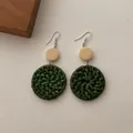 Close-up of bohemian green woven rattan earrings with small wooden disc and metal hook - Green Rattan Round Disk (B345)