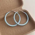 Close-up of light blue lacquer hoop earrings in a vintage box with silver clasp detail - Large Circle / Blue