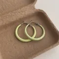 Nahaufnahme hellgrüner Creolen mit mattem Finish auf einer strukturierten Schale - Kleiner Kreis / Cyan