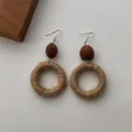 Detail shot of bohemian handmade woven straw earrings with carved wood beads on white linen - Bodhi Hemp Rope Circle (B347)