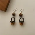 Close-up of handmade wicker basket drop earrings with wooden beads on fabric background - Lotus Bodhi Rattan Basket (B346)