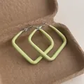 Macro detail of avocado green lacquered square hoop earrings in a rustic gift box - Large Square / Cyan