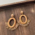 Close-up of bohemian woven raffia earrings with fan-shaped texture on a wooden tray - Oval Half Circle Tassel Brown (A303)