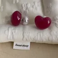 Macro shot of asymmetrical deep red glazed heart earrings with large white pearl backings - Heart / Purple