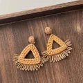 Detail of handmade raffia earrings with woven triangles and fringe on dark wood - Triangle Tassel Wood Color (A306)