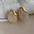 Dettaglio degli orecchini in resina a goccia con trama marmorea e placcatura in oro - Bianco avorio