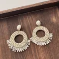 Detailed macro shot of bohemian cream raffia woven earrings on a rustic wood background - Hollow Round Half Circle Tassel Beige (A310)