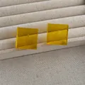 Detailed view of translucent yellow acrylic cube earrings on a linen texture display - Yellow